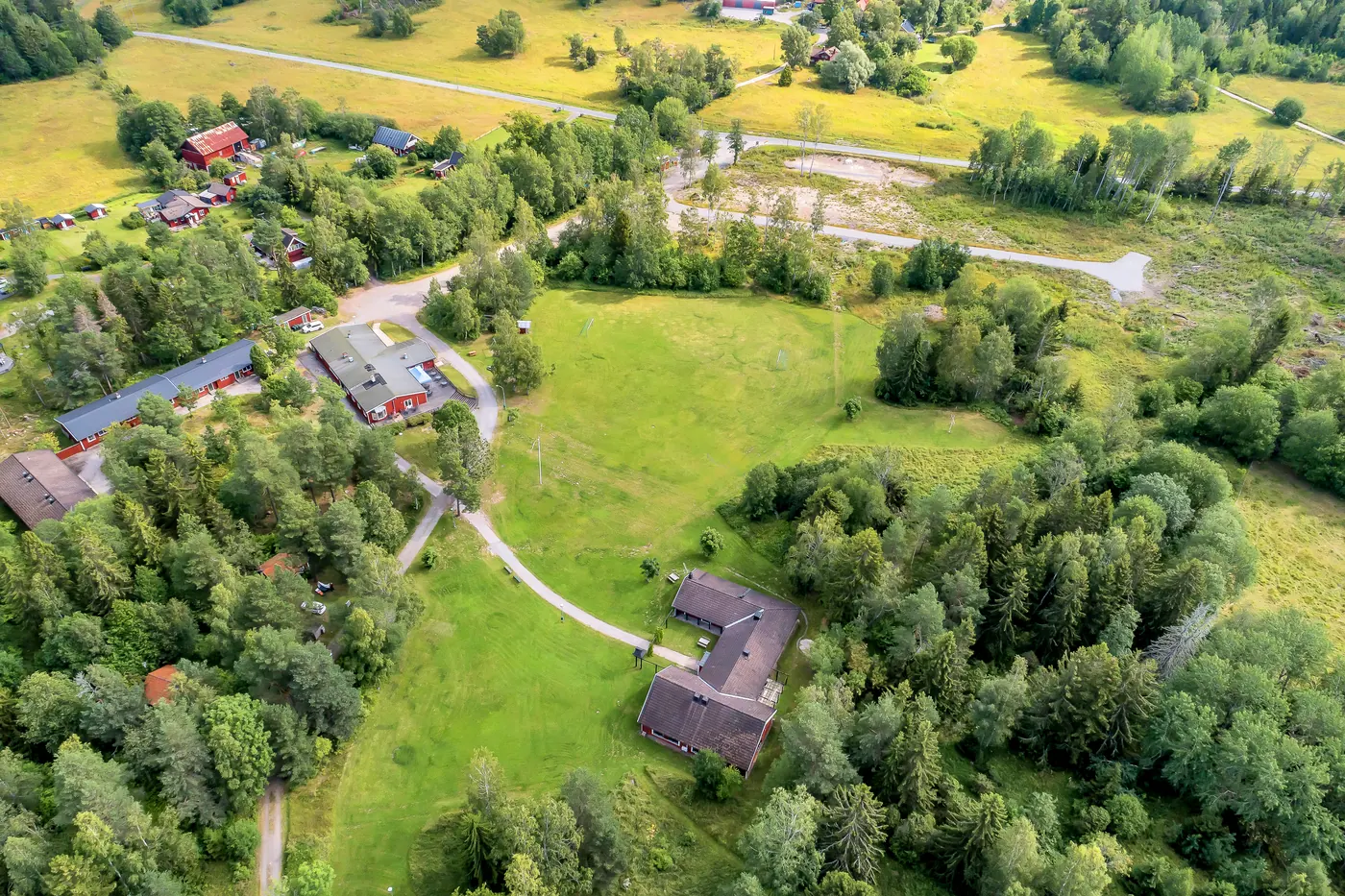 Flygbild över gården med husen utspridda längs gångvägar och gräsytor